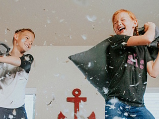 Symbolbild: Zwei Kinder bei einer Kissenschlacht. (Allen Taylor - unsplash.com)